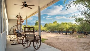 A covered patio with a vintage cart and a ceiling fan.