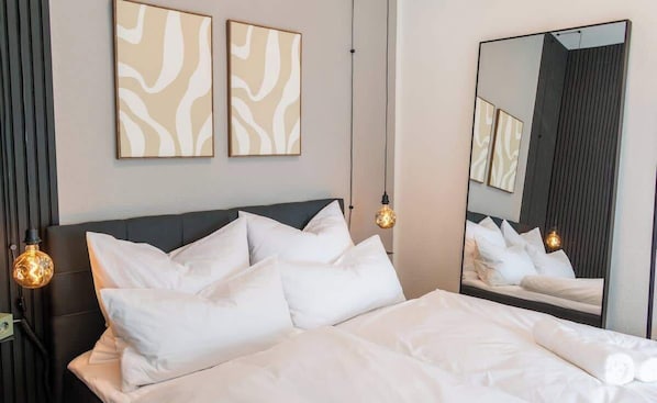 Ein modernes Schlafzimmer mit einem Bett, zwei Wandleuchten und zwei abstrakten Gemälden.