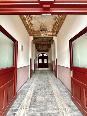 A hallway with a patterned floor, wooden doors, and a decorative ceiling.