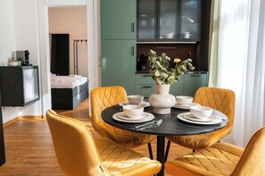 A dining area with a round table, four chairs, and a vase with flowers.