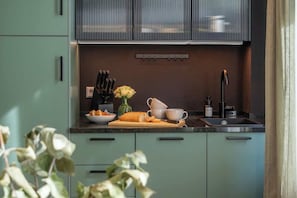 Eine moderne Küche mit türkisfarbenen Schränken, einer Holzausziehtafel und einem Spülbecken.