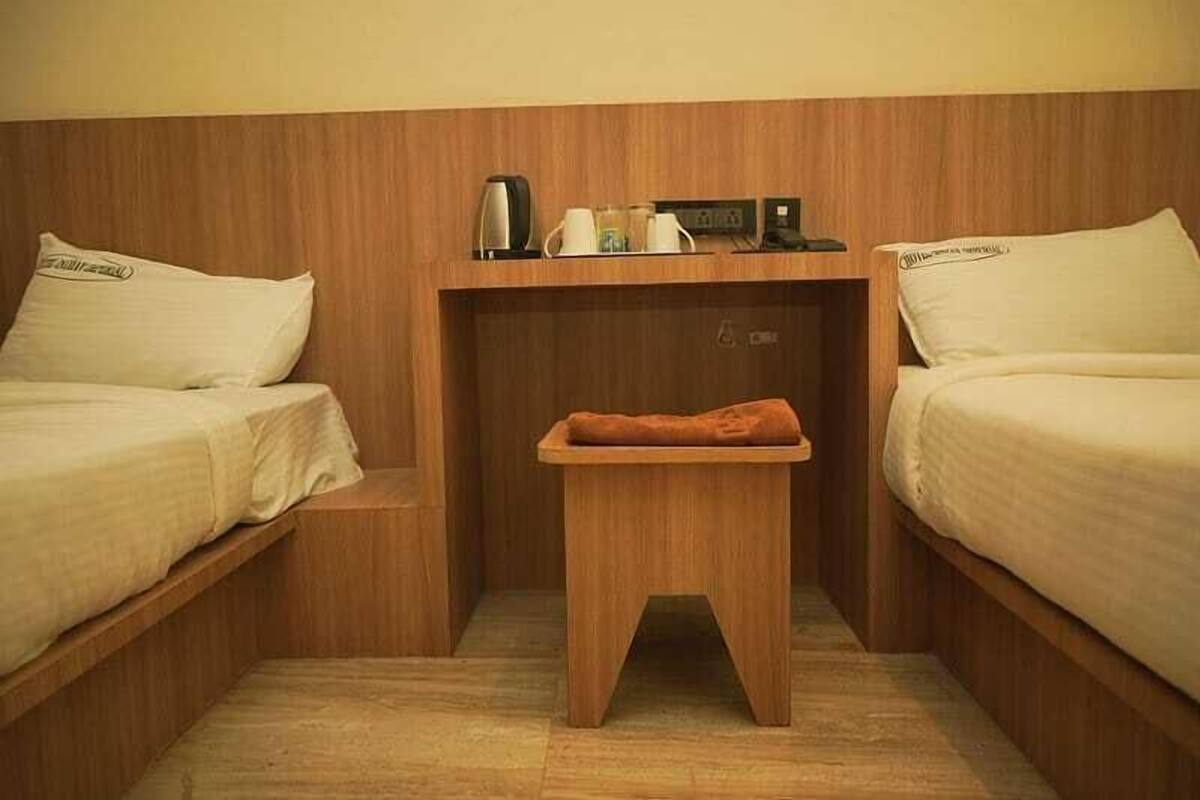 A small, cozy room with two beds, a wooden nightstand, and a small table with a blanket.