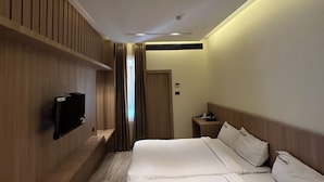 Een moderne hotelkamer met een groot bed, een flatscreen televisie aan de muur en een nachtkastje.