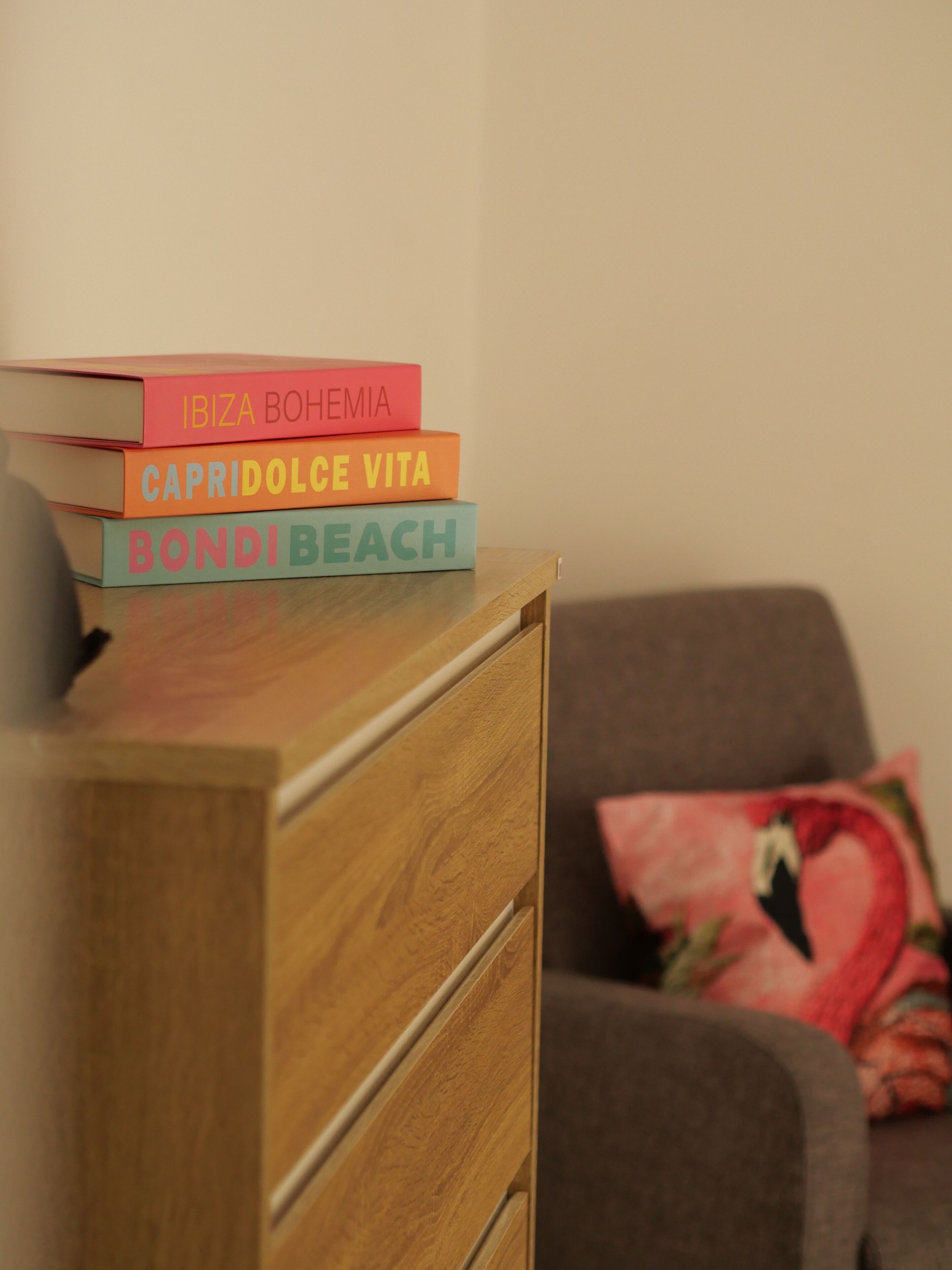 A stack of books on a wooden dresser.