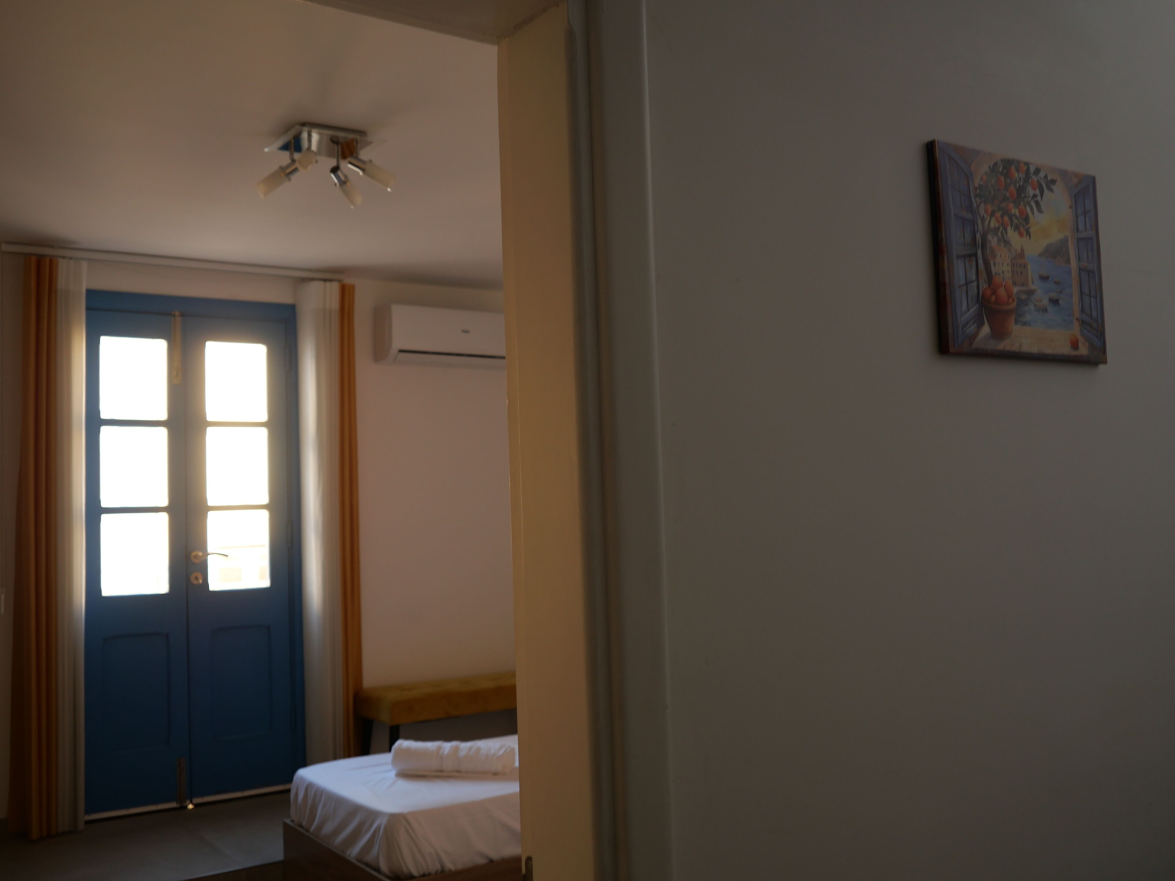 A bedroom with a bed, a blue door, and an air conditioning unit.
