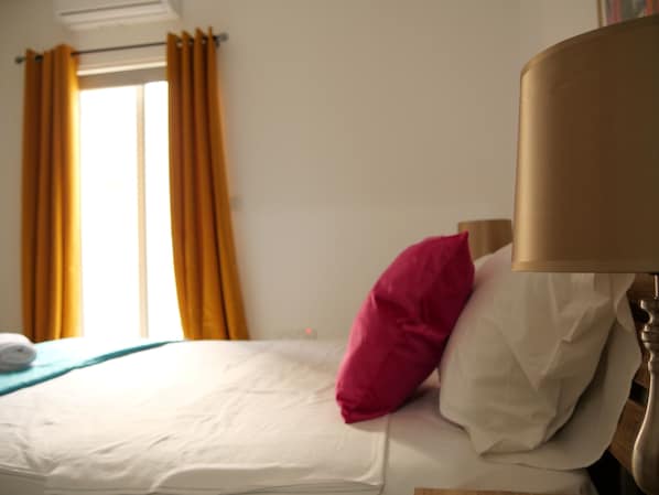 A hotel room with a bed, a window with curtains, and a lamp. - Casa Isla (Sliema)