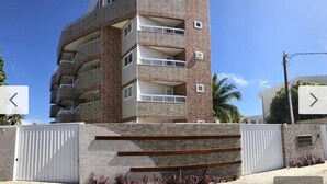 Un edificio de varios pisos con fachada de ladrillo, balcones y una entrada protegida por una reja.