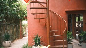 A spiral staircase leading to an upper floor, surrounded by potted plants and a bamboo fence. - DAINOI Hue Homestay (Hue)