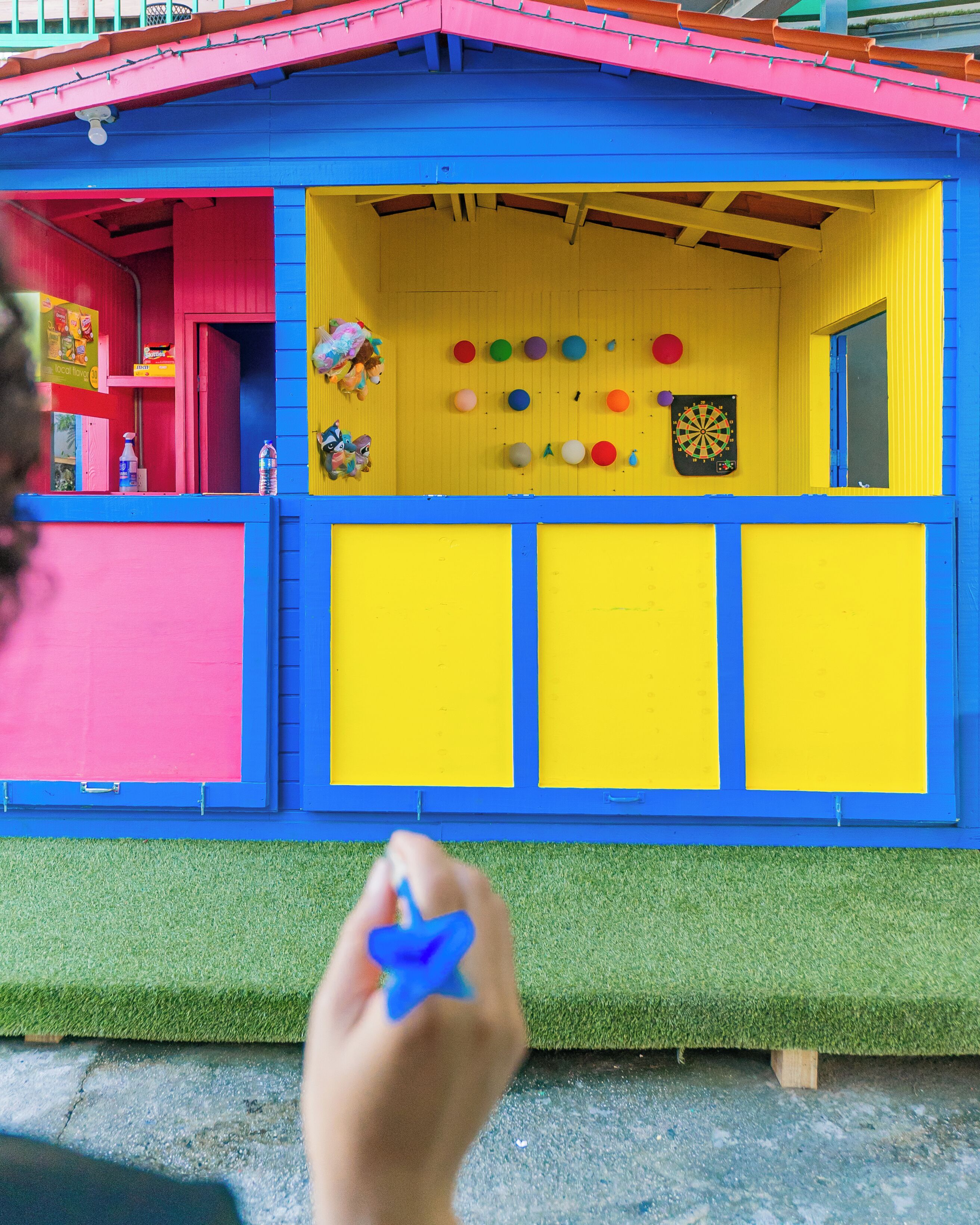 A colorful dollhouse with a red door, a blue roof, and a yellow interior.