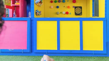 A colorful dollhouse with a red door, a blue roof, and a yellow interior.