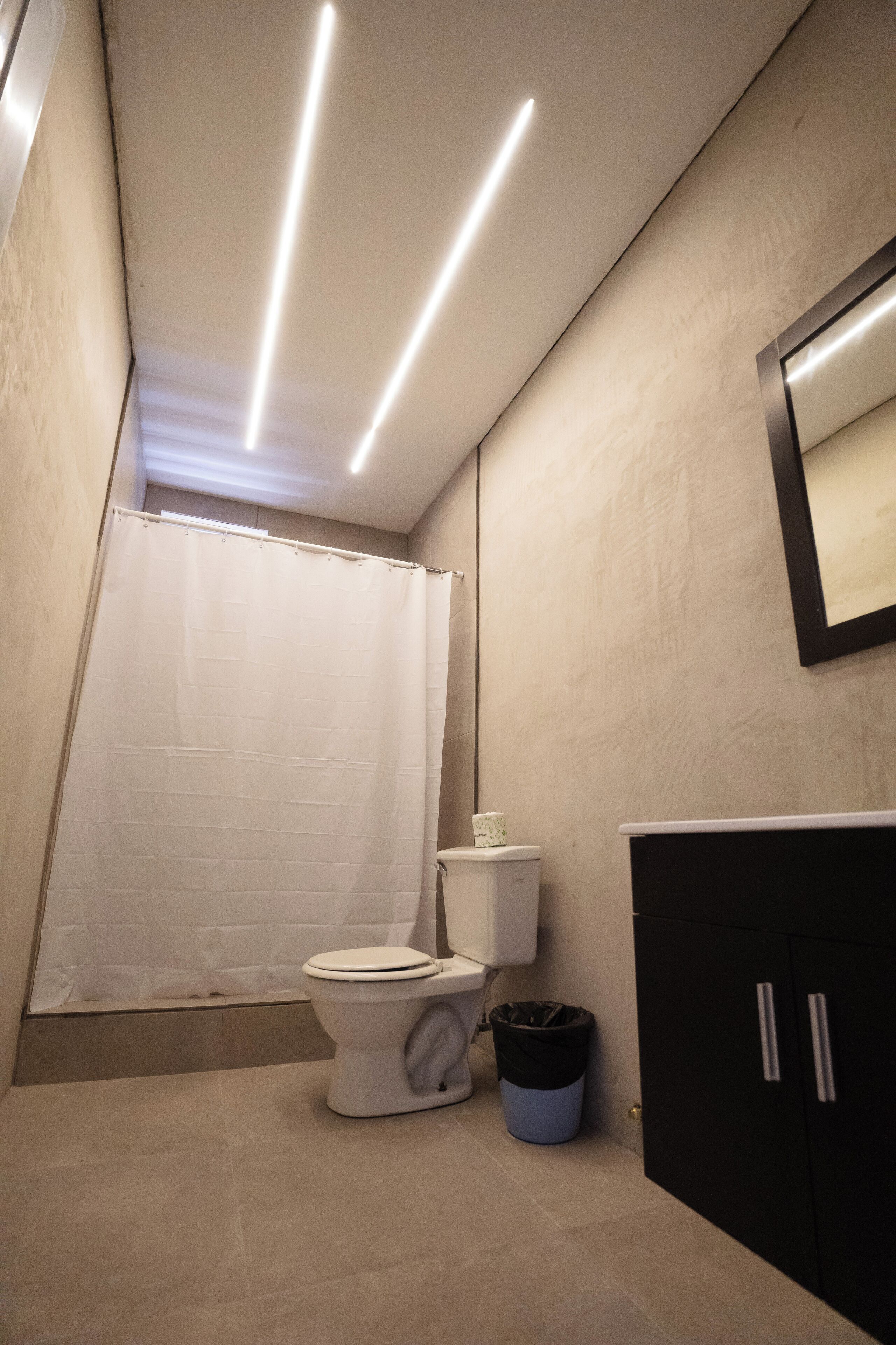 Ein modernes Badezimmer mit Toilette, einem schwarzen Schrank und einer Duschvorhang.