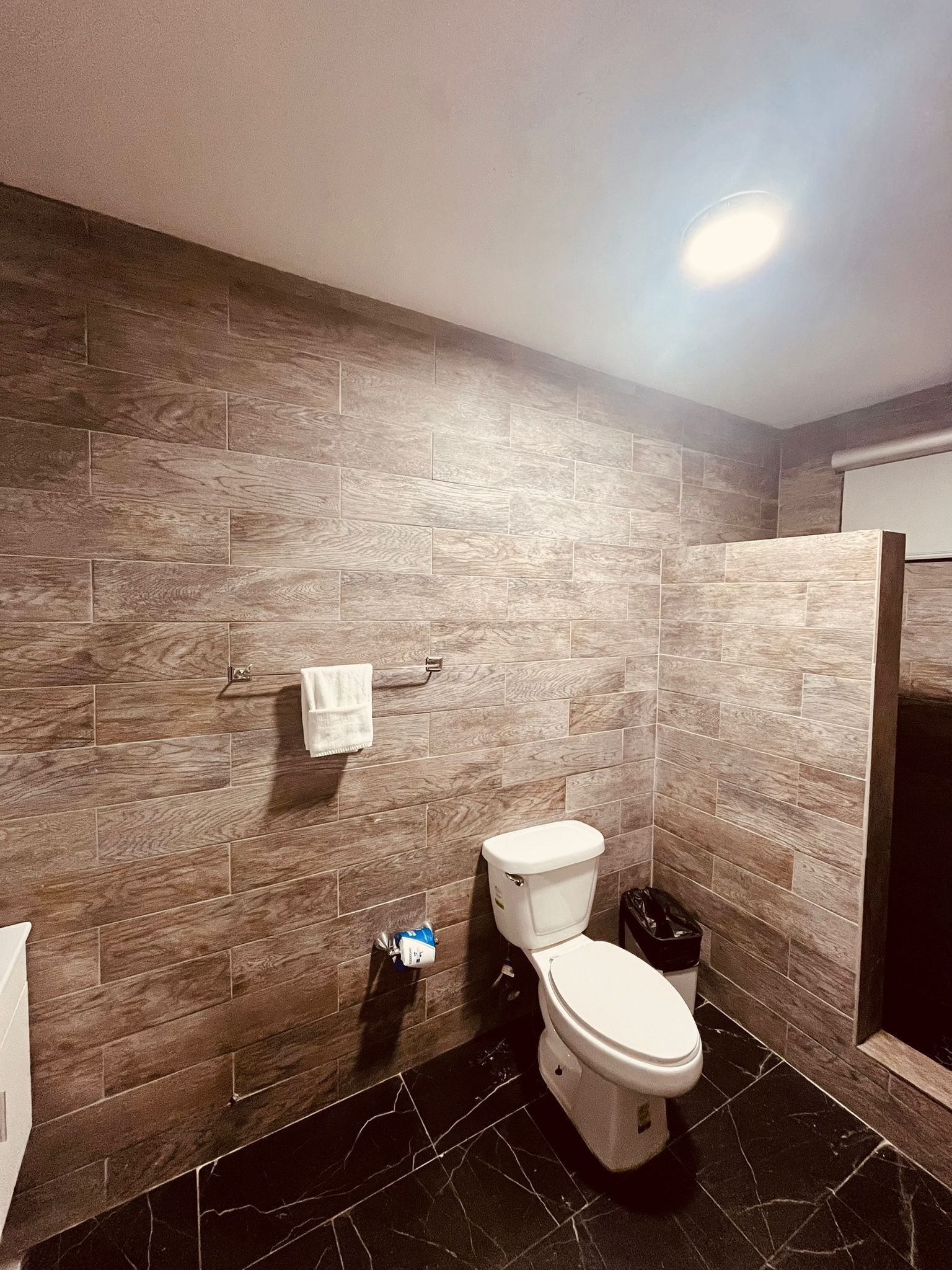 Une salle de bain équipée de toilettes, d’un porte-serviettes et d’une poubelle.