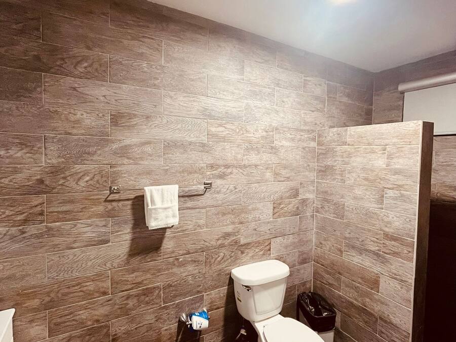 A bathroom with a toilet, a towel rack, and a trash bin.
