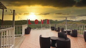 A terrace with wicker furniture, a white railing, and a 'LOVE' sign. - Hotel Vista Verde (Yauco)
