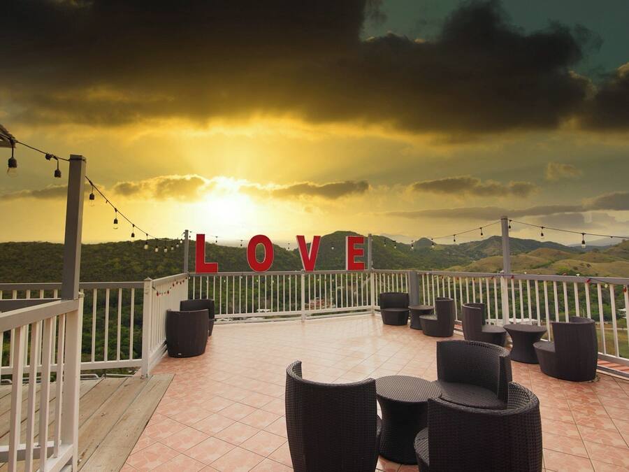 Eine Terrasse mit Korbmöbeln, einem weißen Geländer und einem 'LOVE'-Schild.