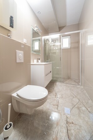 A modern bathroom with a toilet, sink, and shower area. - Apartments Agape (Petrovac)