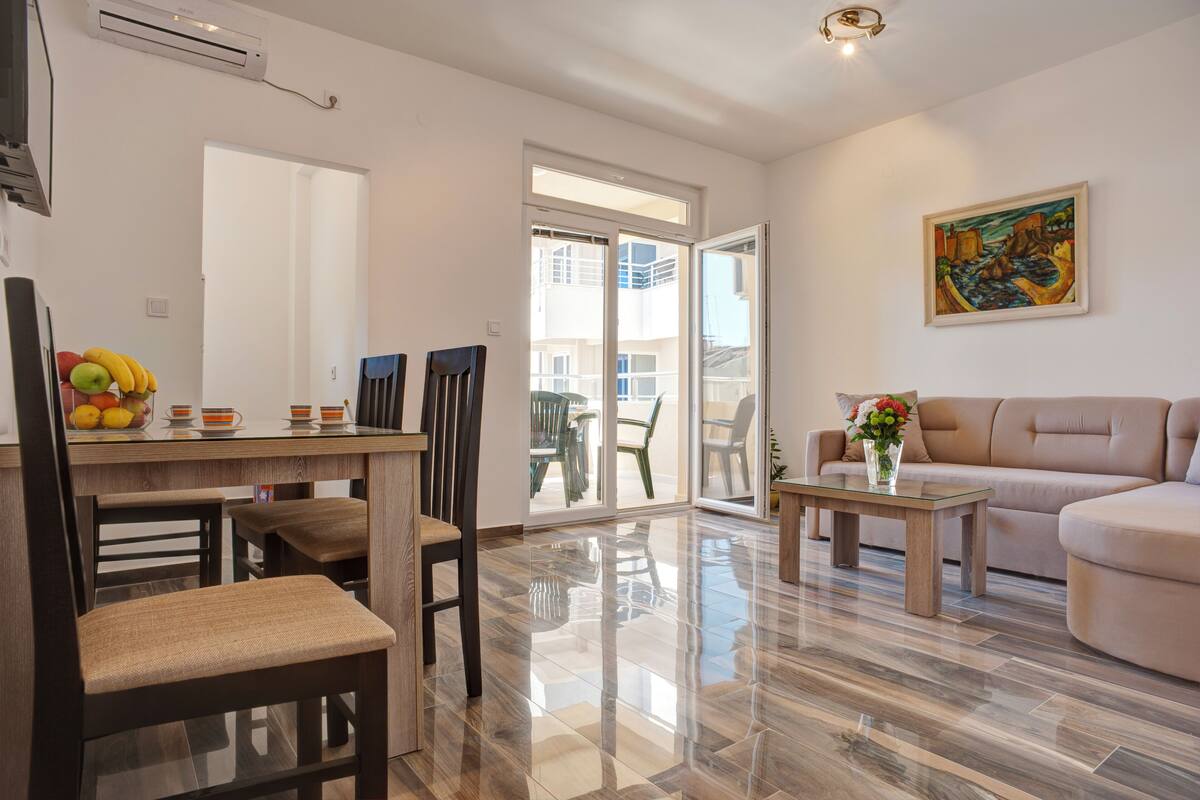 A modern living room with a sofa, a dining table with chairs, and a glass coffee table.