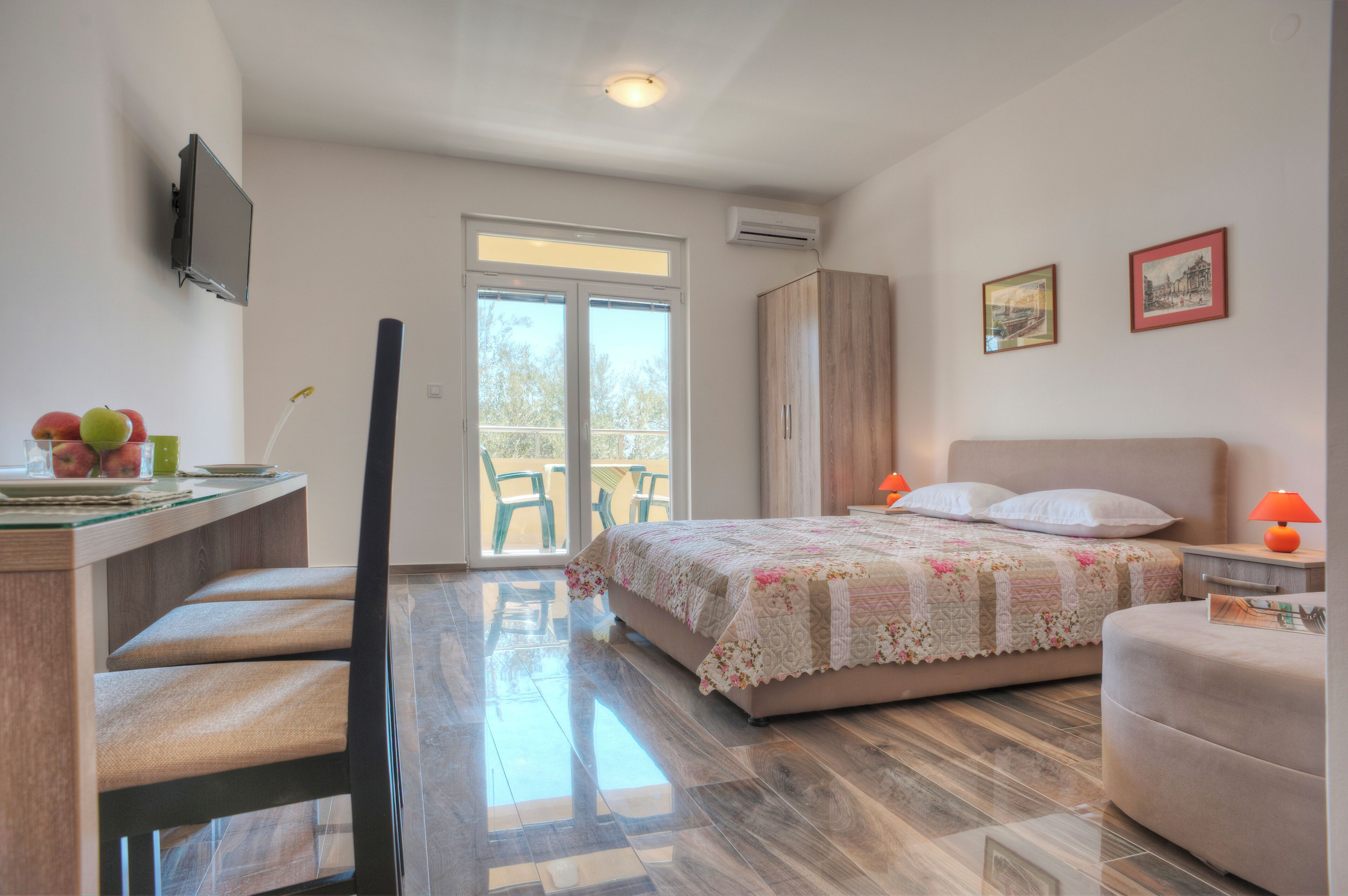 Une chambre à coucher comprenant un lit, un bureau avec une chaise, une télévision et un balcon avec des chaises.