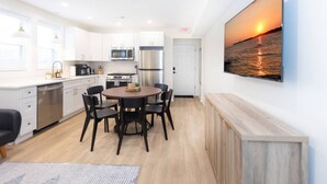 A modern kitchen with white cabinets, stainless steel appliances, and a dining area with a round table and chairs.