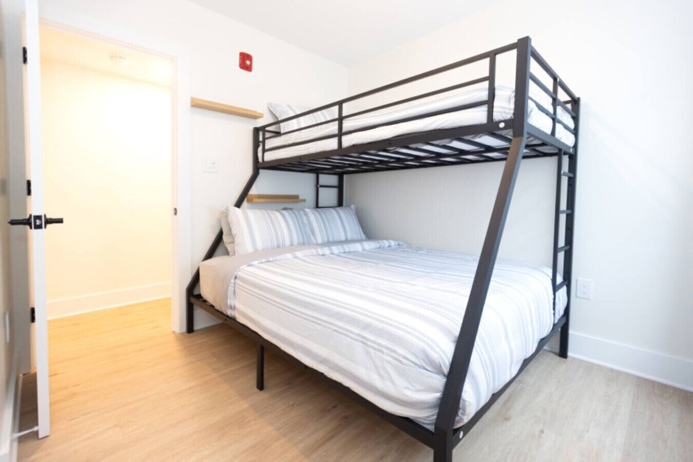 Ein Stockbett mit Holzboden und weißen Wänden.
