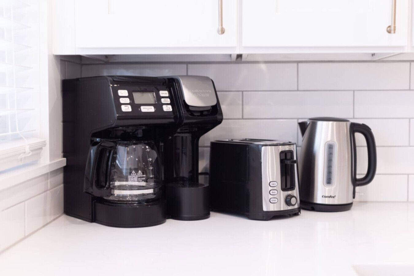 A kitchen with a coffee maker, toaster, and kettle.