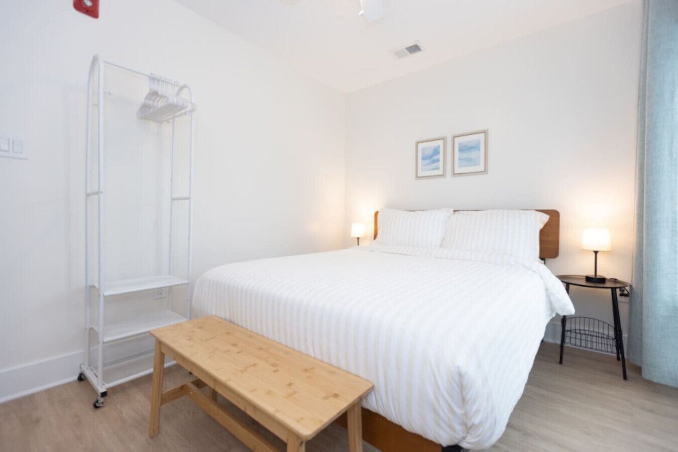 Une chambre à coucher comprenant un lit, des tables de chevet, un banc, une armoire et une étagère fixée au mur.