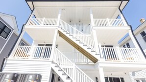 A multi-story building with a central staircase, balconies, and a covered outdoor area. - Steps to THE Beach – 3 BDR Condo + Parking (Wildwood)