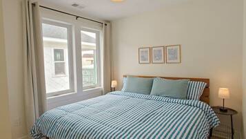 A bedroom with a large bed, two bedside lamps, a ceiling light, and two framed pictures on the wall.