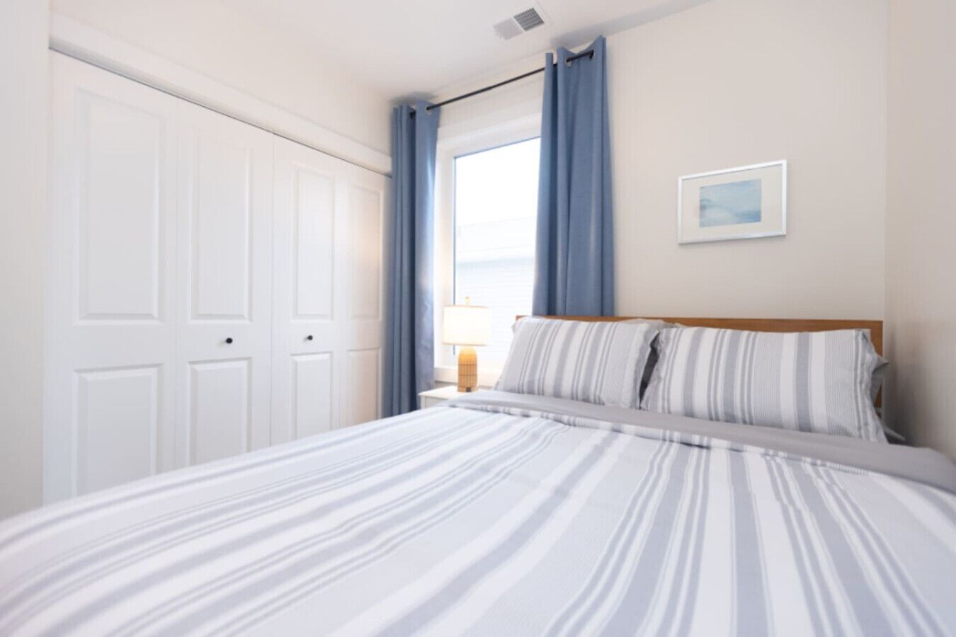 Una camera da letto con un letto, un comodino, una finestra con tende e una porta.