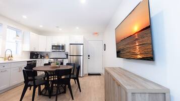 A modern kitchen with white cabinets, stainless steel appliances, and a dining area with a round table and chairs.