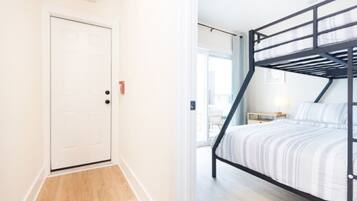 A room with a bunk bed, a white door, and a small table with a lamp.