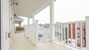 A covered porch with white railings and a bench, leading to a staircase. - 500 ft to boardwalk, 3 bdr condo (Wildwood)