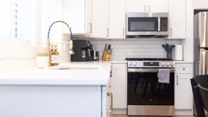A modern kitchen with white cabinets, a stainless steel oven, a microwave, and a coffee maker. - 500 ft to boardwalk, 3 bdr condo (Wildwood)