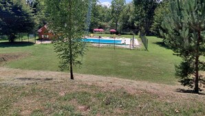 A backyard with a swimming pool, a wooden cabin, and a fenced area with trees. - Spacious mobile home with terrace and lake view, ideal for families. (Bairon et ses environs)