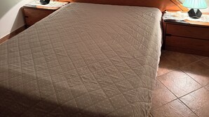 Un lit recouvert d’une courtepointe, deux tables de chevet avec des lampes et une tête de lit en bois.