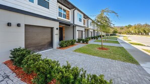 A modern residential building with a garage, a well-maintained lawn, and a clear sky.