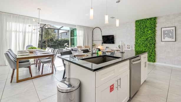 A modern kitchen with a central island, white cabinetry, and a green vertical garden wall.