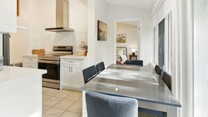 A modern kitchen with white cabinetry, a stainless steel oven, and a glass dining table.