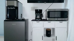 A compact kitchenette with a refrigerator, coffee maker, microwave, and a flat-screen TV. - Charming studio in soothing North Las Vegas with AC (North Las Vegas)