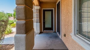 A building entrance with a concrete column, a door with a window, and a window with blinds. - Charming studio in soothing North Las Vegas with AC (North Las Vegas)