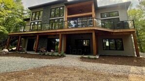 A modern two-story house with a balcony, large windows, and a stone facade. - Newly constructed, beautiful, modern lakehouse with new barrel sauna  (Mactier)
