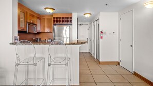 A modern kitchen with wooden cabinets, stainless steel appliances, a white countertop, and two clear bar stools. - Oceanfront Oasis Couple s Retreat San Juan (San Juan)