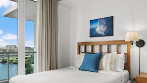 Une chambre d’hôtel avec un grand lit, une vue sur la ville et un tableau au mur.