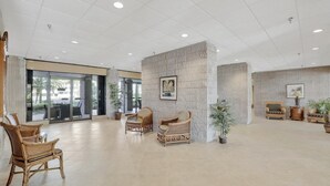 Un hall d’entrée spacieux, doté de meubles en osier, d’un pilier en marbre et d’une grande fenêtre.