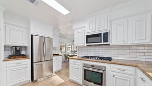 Una cocina moderna con armarios blancos, electrodomésticos de acero inoxidable y salpicadero de azulejos.