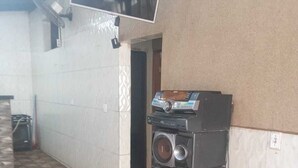 Une pièce avec un sol carrelé, un téléviseur fixé au mur et une pile d’enceintes posée sur une palette en bois.