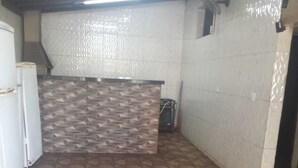 Une cuisine avec un mur arrière décoré de motifs, un sol imitant la pierre et un réfrigérateur blanc.