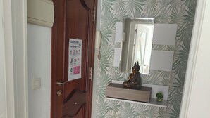 Ein Flur mit einer Holztür, einem Spiegel und einem gefliesten Boden.