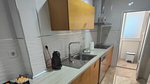 Eine moderne Küche mit Marmorarbeitsplatte, Holzschränken, einer Kaffeebar und einem Spülbecken.