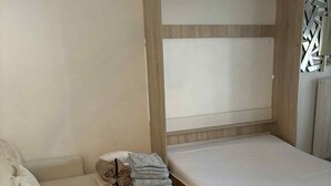Una habitación pequeña con cama, sofá y una mesita.